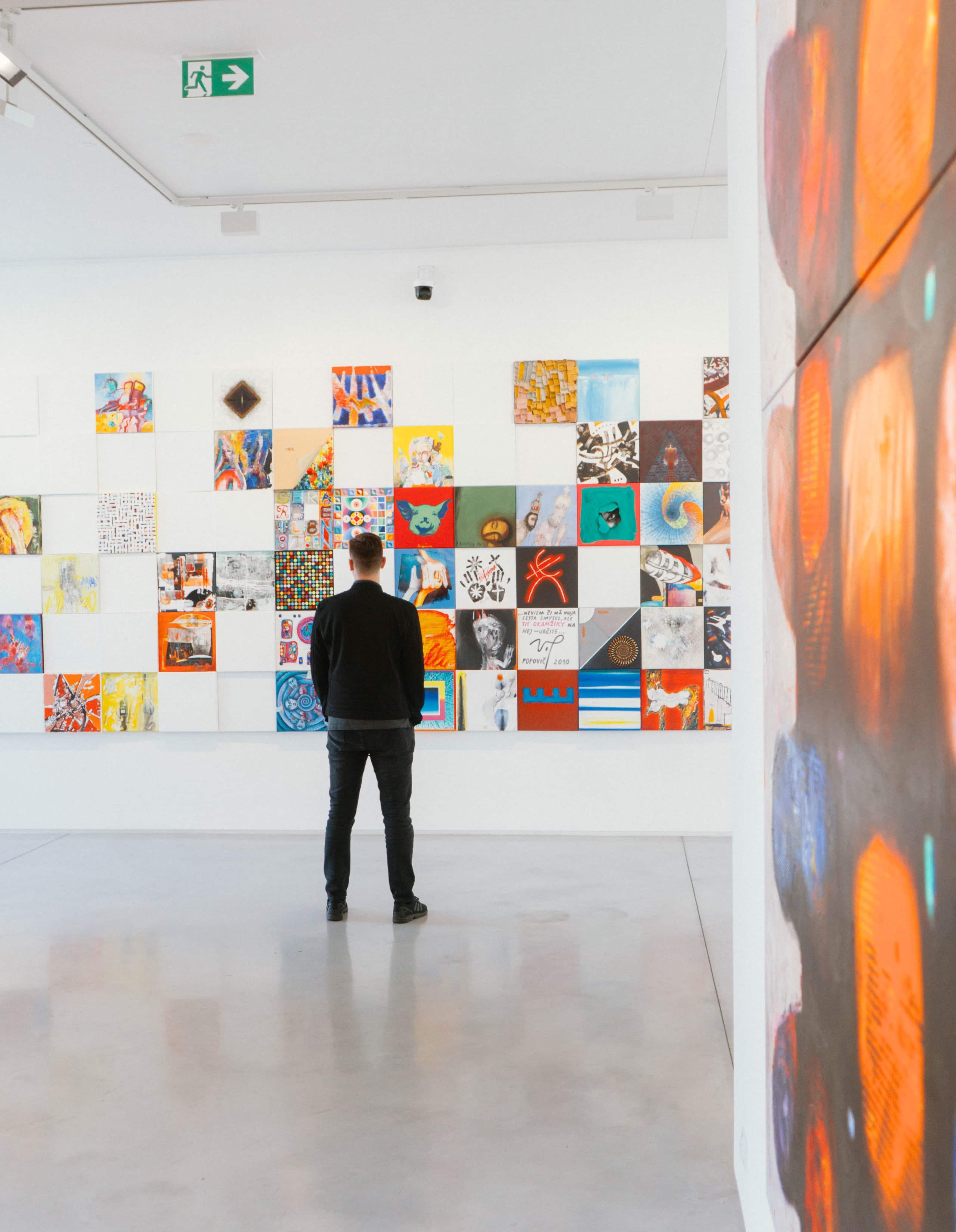 a man facing a wall of art work